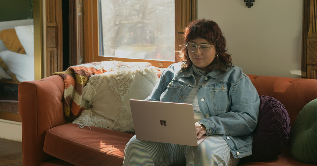 Woman sitting on couch using a laptop.